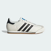 The Core White K 74, highlighting the clean black 3-Stripes and the slim, low-profile athletic silhouette.