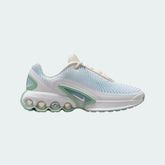 Nike Air Max DN Juniors' running trainers in soft pearl light green and off-white, side profile showing visible Dynamic Air unit in the heel, textured upper, and sleek silhouette.
