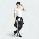 Adidas Adibreak Button Track Pants in black with a subtle animal print, front view showing the elastic drawcord waist and the full line of snap buttons down the side.