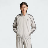 Front view of an Adidas Superstar Men's Bonded Track Top in Medium Grey (IW7318) on a model, showcasing its full design.