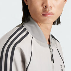 Close-up side profile of the Adidas Superstar Men's Bonded Track Top in Medium Grey (IW7318), highlighting the iconic three stripes on the shoulder.