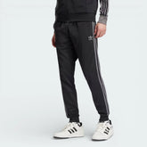 Front profile of the black slim-fit track pants, showing the tapered leg and the subtle contrast of the Grey Four branding.