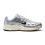Capturing the 2000s retro running silhouette, detailing the white open-mesh upper, horizontal and vertical metallic silver leather overlays, dimensional moulded black Swoosh, sculpted white foam midsole, and black rubber outsole edge.