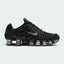 Highlights the lateral profile showing the metallic silver Nike Swoosh, glossy black TPU cage, breathable black mesh quarter, metallic silver Shox columns extending the full length of the sole, and the subtle RealTree camo collar lining.