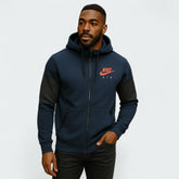Man wearing a navy blue hoodie with Nike logo on a light gray background