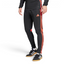 Side profile of the Black and Lucid Red Tiro 25 pants, highlighting the vibrant red 3-Stripes and the tapered leg silhouette.