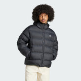 Adidas Tonal Hooded Puffer Jacket in black, front view shown a model showing the full-zip closure, high collar, and side pockets.