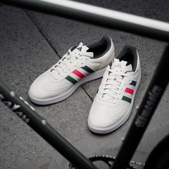 White sneakers with colorful stripes on a gray pavement