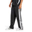 Studio side profile view of a male model wearing the adidas Originals Adibreak Pants in black, highlighting the regular fit, classic white 3-Stripes, functional snap-button side panels, and retro Adibreak leg patch.