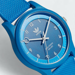 Close-up zoom on the digital watch face of the Adidas Originals Project One R Watch, highlighting the time display and the embossed Adidas Originals logo.