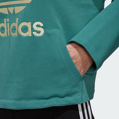 Close-up zoom on the Adidas Premium Hoodie Trefoil Overhead Women's in noble green, showing the plush fleece fabric texture and the detailed metallic gold Trefoil logo.