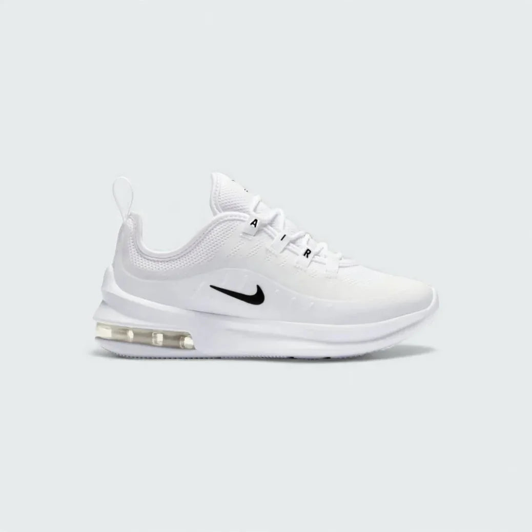 Nike Air Max Axis Children's trainers in white with black accents, side profile showing layered mesh and synthetic upper, prominent visible Max Air unit in the heel, and Nike Swoosh.