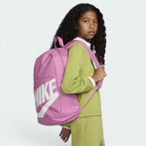 Child wearing a pink Nike backpack on a white background