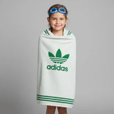 Child wrapped in an Adidas towel with a gray background