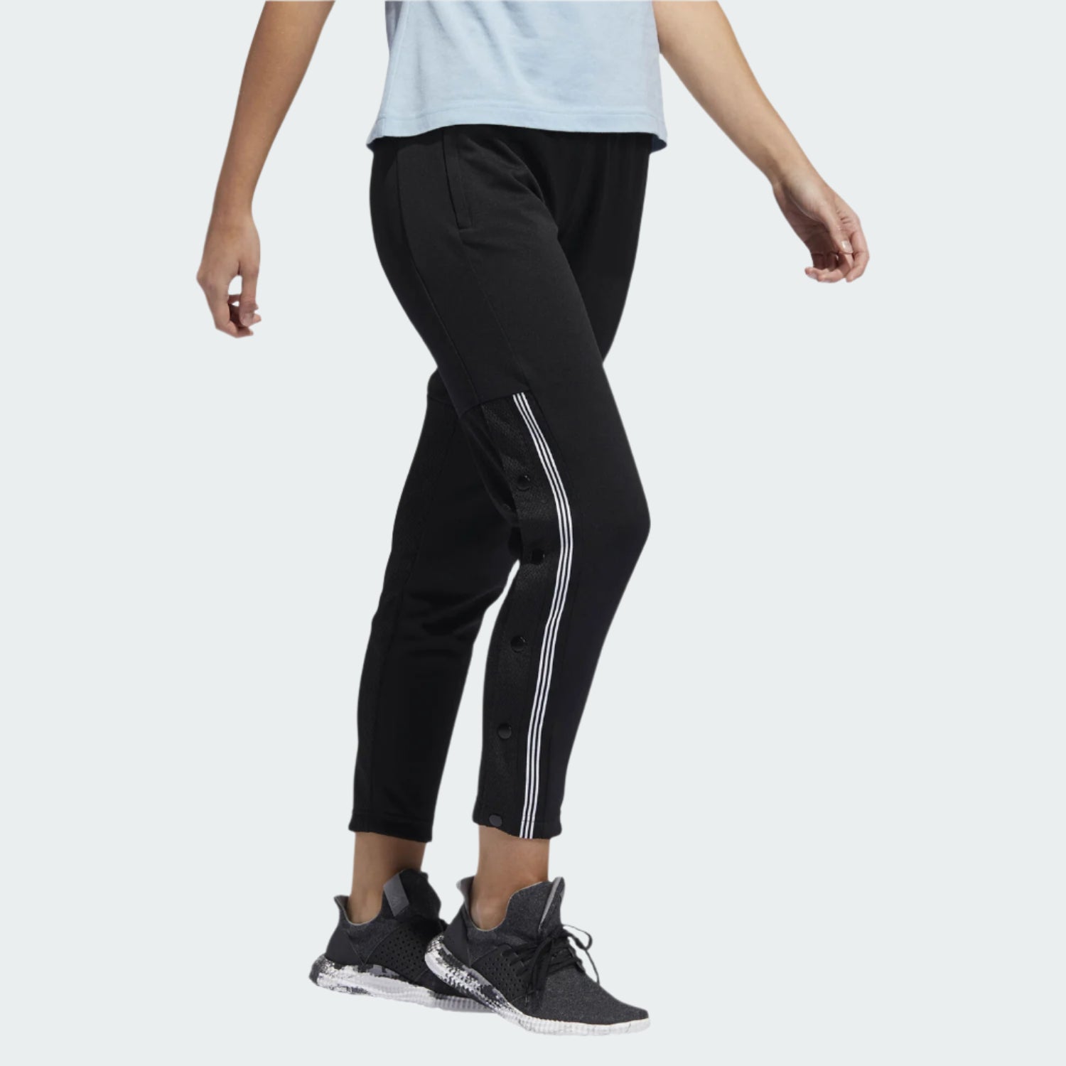 Adidas 7/8 Cropped Snap Pants Women's in black worn by a woman, showcasing the cropped length, side snap details, and relaxed fit in a casual setting.