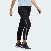 Adidas 7/8 Cropped Snap Pants Women's in black worn by a woman, showcasing the cropped length, side snap details, and relaxed fit in a casual setting.