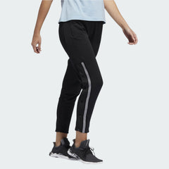 Adidas 7/8 Cropped Snap Pants Women's in black worn by a woman, showcasing the cropped length, side snap details, and relaxed fit in a casual setting.