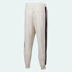 Nike Men's Tribute Woven Track Pants in light beige, back view showcasing the plain design, ribbed cuffs, and comfortable fit.