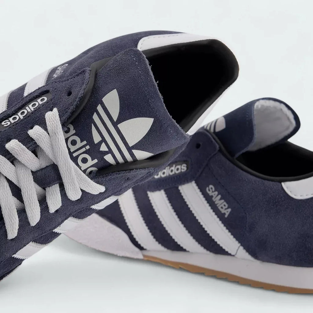 Close-up zoom on the front of the Adidas Samba Super Men's navy trainers, showing the suede T-toe, perforated tongue, and lacing system.