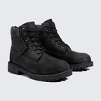Angled view of two Timberland 6 Inch Premium Juniors' black boots, side by side, showcasing their classic waterproof design and sturdy build.