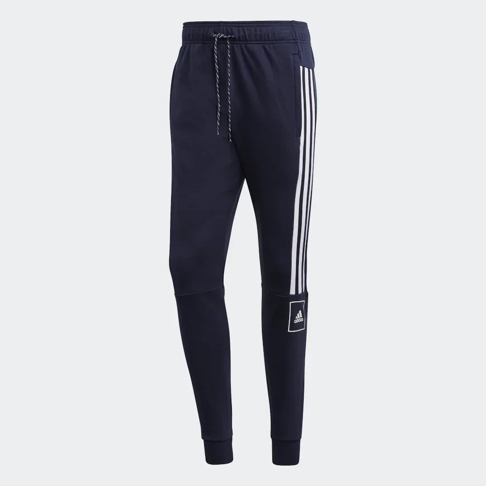 Navy blue Adidas jogger pants with white stripes on a light gray background