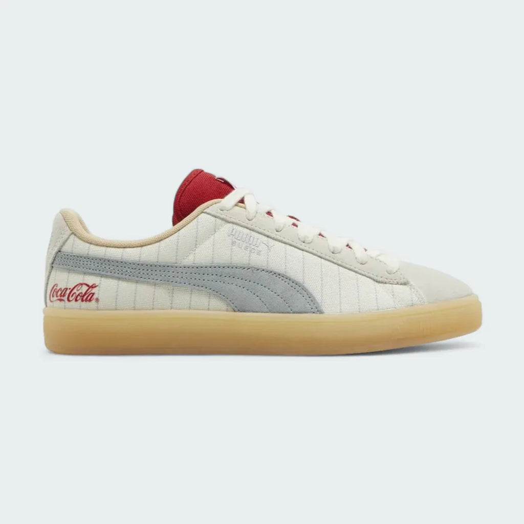 Puma Suede x Coca-Cola Unisex trainers in white suede with a red Formstrip, side profile showing the classic silhouette and a Coca-Cola branded heel tab.