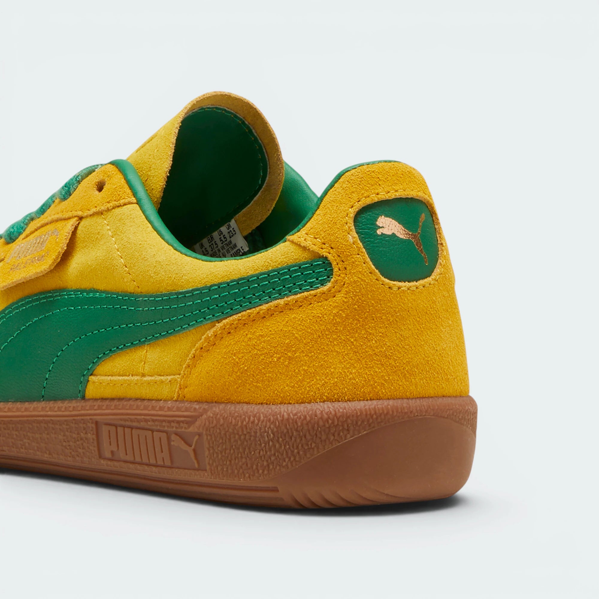 Focuses on the contoured shape of the green leather heel tab, showing the clean, screen-printed PUMA cat logo sitting above the texturized gum sole spine.