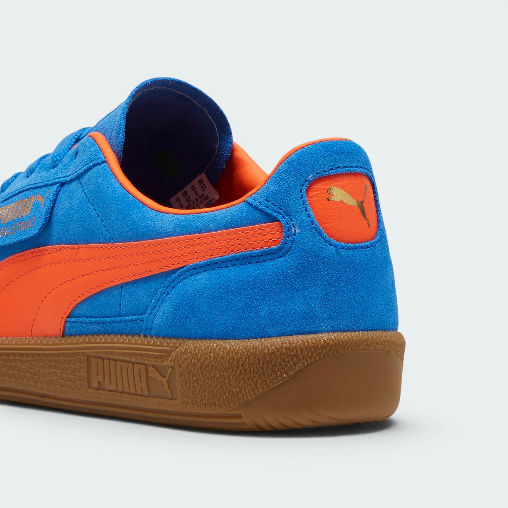 Focuses on the contoured shape of the flame orange leather heel tab, showing the clean, screen-printed PUMA cat logo sitting above the texturized gum sole spine.