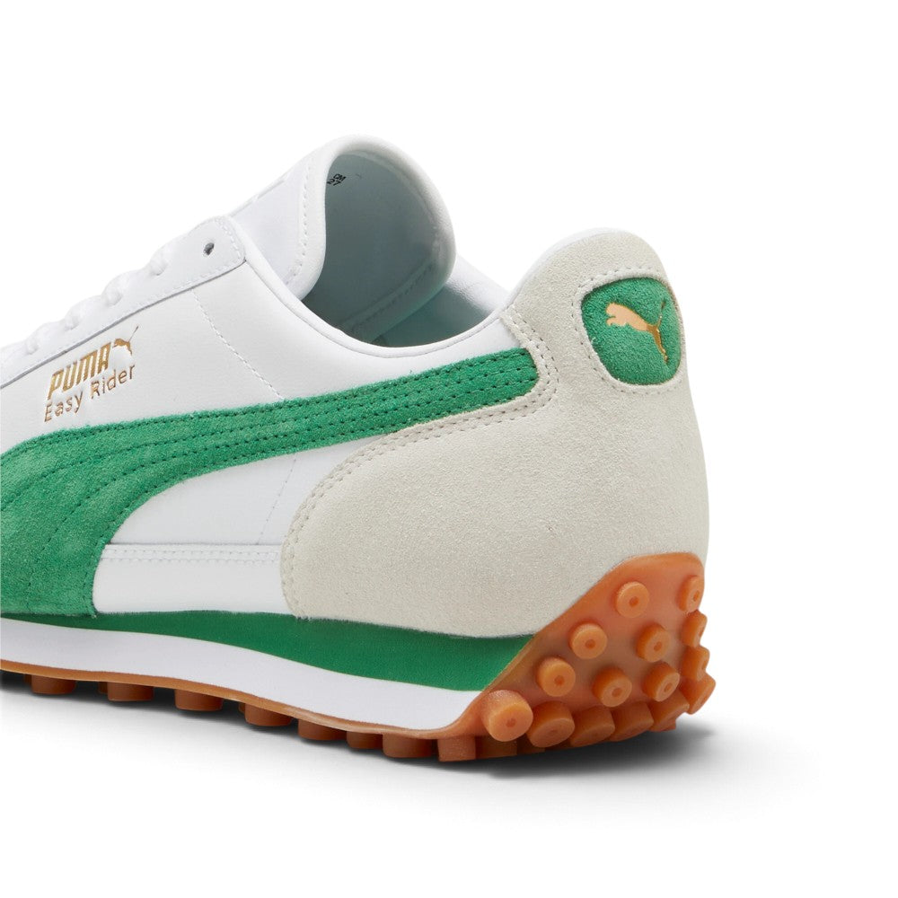 Focuses on the rear three-quarter profile, displaying the off-white suede heel counter, kelly green leather heel tab stamped with a gilded metallic gold PUMA Cat logo, white leather upper quarter, green-accented white EVA wedge midsole, and the upward-wrapping gum rubber studded outsole.