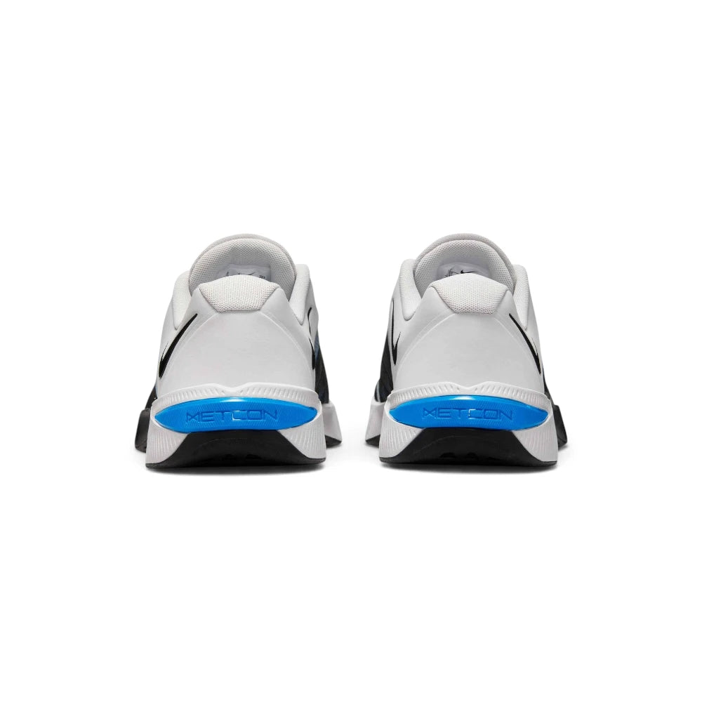 Rear view of both shoes showcasing the white padded heel collars, textured grey heel tabs, white midsoles, and bright blue heel clips debossed with "METCON" branding above black rubber traction bases.