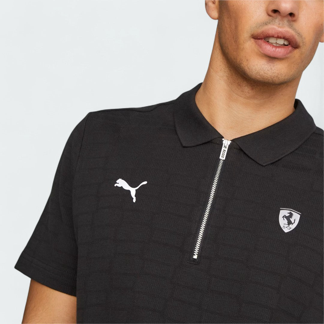 Close-up zoom on the Puma Ferrari Jacquard Polo in black, showing the intricate woven jacquard pattern, the embroidered Ferrari Scudetto shield, and the Puma logo.