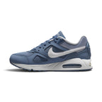 A Nike Air Max sneaker in a muted slate blue colorway, featuring a white Swoosh and a white midsole with a visible air cushion unit.