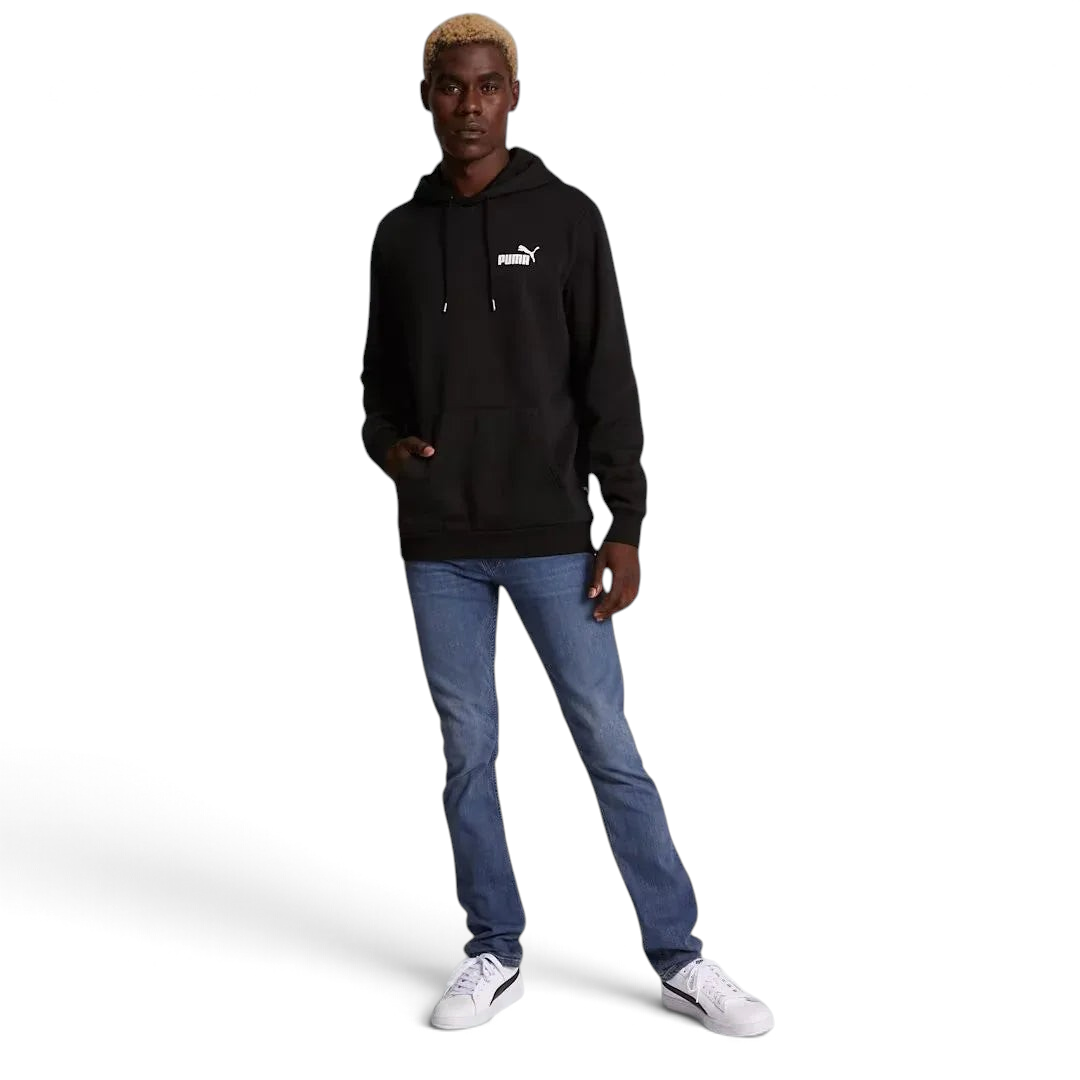 distant model view off the Puma Essential Small Logo Overhead Fleece Hoodie in black, showing the soft fleece fabric texture and the detailed embroidered Puma Cat Logo.