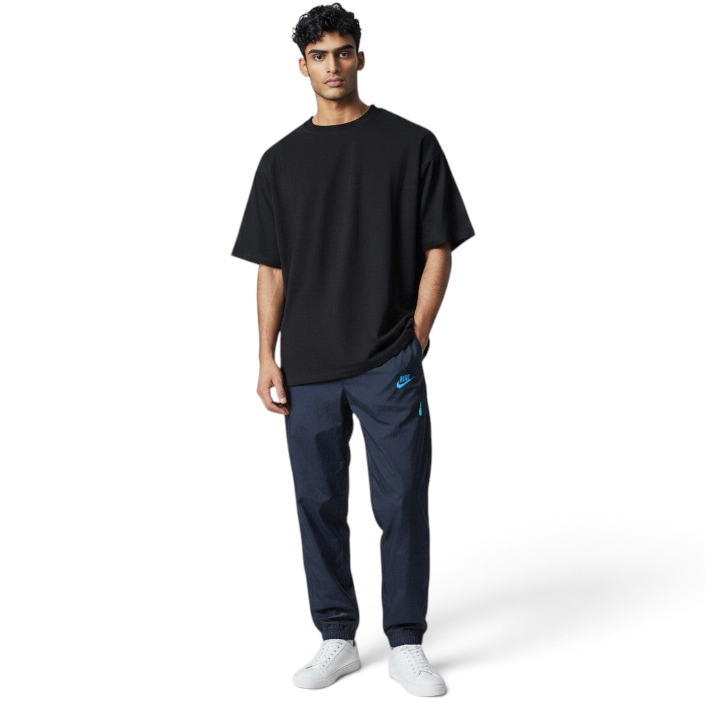 Man wearing a black oversized t-shirt and navy pants with a brand logo on a light gray background Main image