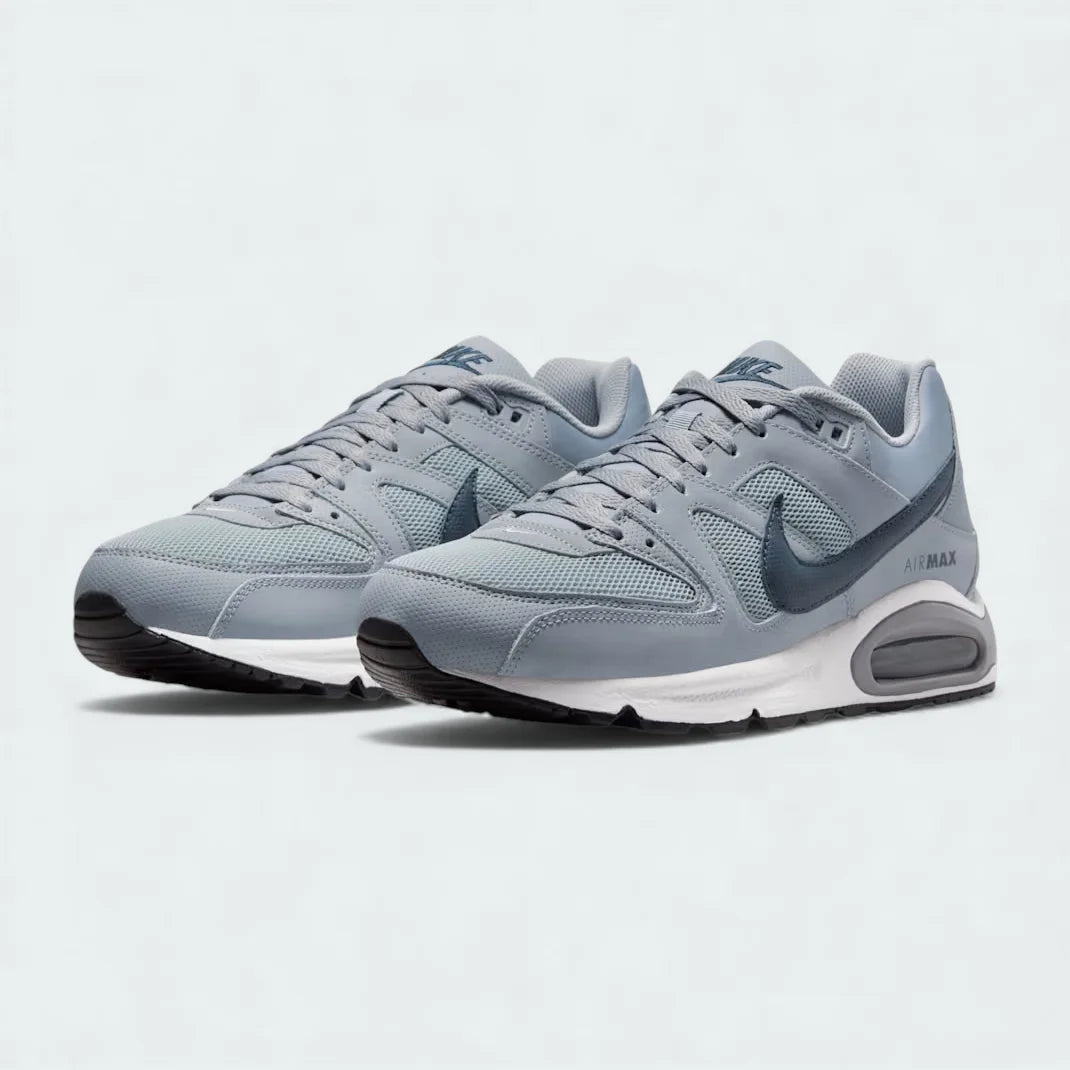 Angled view of two Nike Air Max Command Men's grey trainers, side by side, showcasing their classic aesthetic and cushioned design.