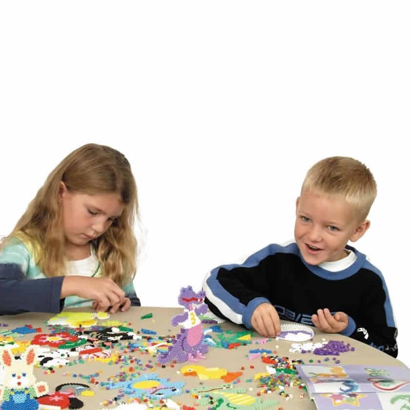 Two children playing with colorful toys at a table on a white background