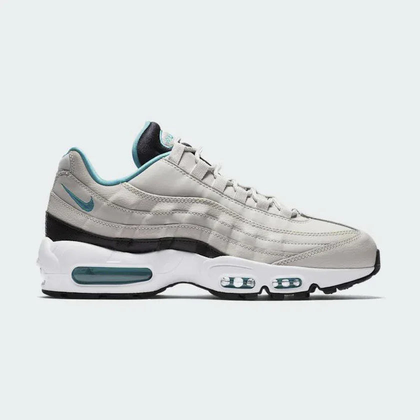 Nike Air Max 95 Essential Men's running shoes in beige with turquoise and black accents, side profile showing visible Max Air units in the heel and forefoot, and a layered upper. Main image