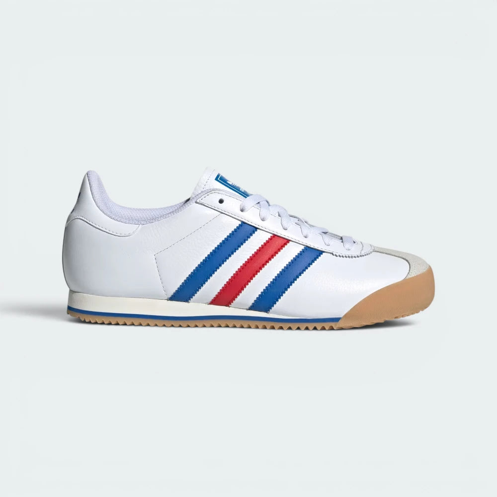 Highlights the high-velocity sweep of the Blue and Better Scarlet serrated 3-Stripes and the professional, velvety depth of the white suede panels leading to the low-profile gum sole.