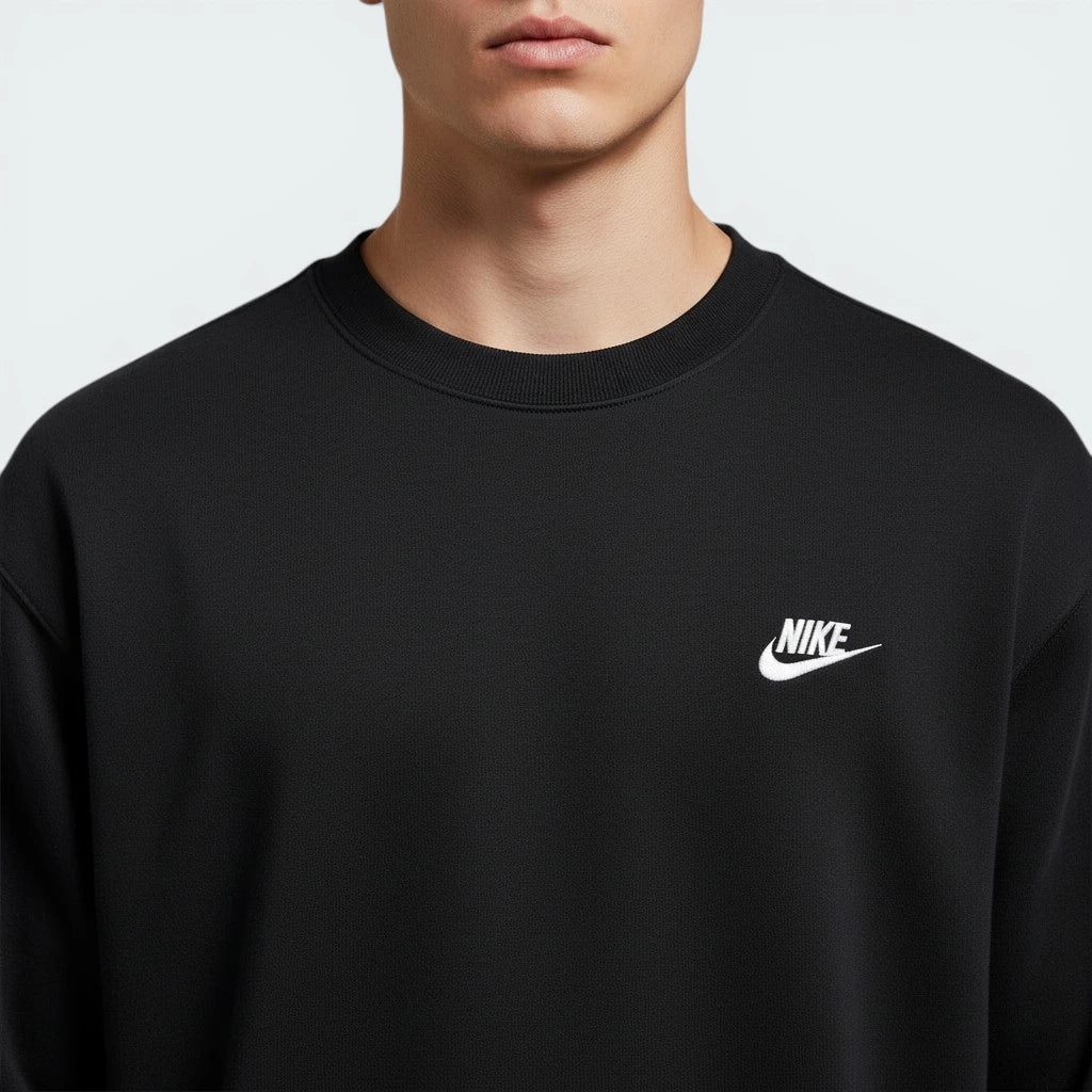 Black Nike sweatshirt with white logo worn by a person on a light gray background