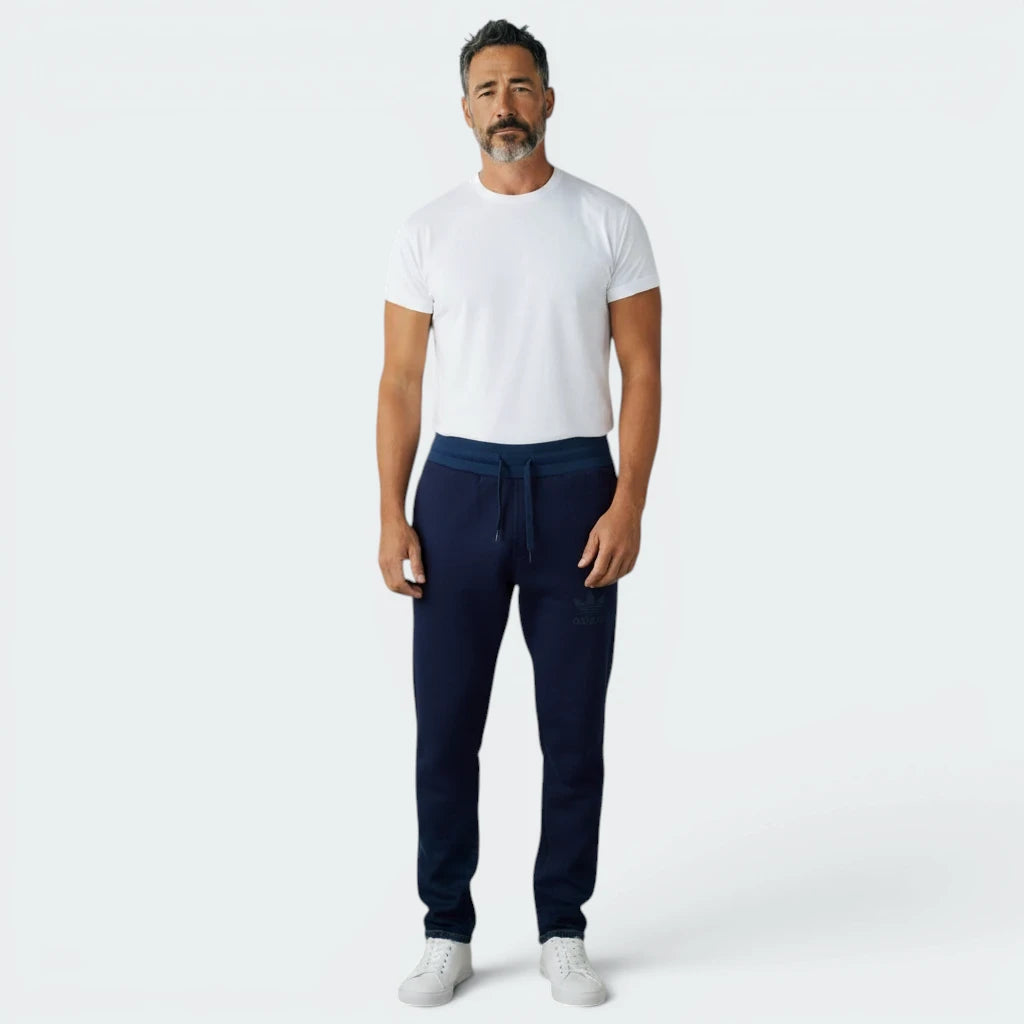 Highlights the tapered leg silhouette and the professional finish of the tonal navy 3-Stripes.
