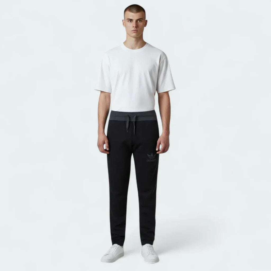 Highlights the high-velocity sweep of the contrast grey 3-Stripes along the side seams, showing the professional, deep matte black texturing of the French terry body and the clean alignment of the Trefoil logo.