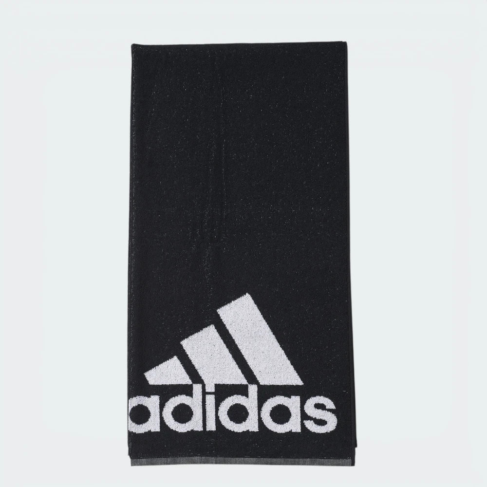 Focuses on the full front profile of the neatly folded towel, highlighting the crisp, high-contrast white adidas Badge of Sport logo block printed squarely against the rich black terry loop background. Main image