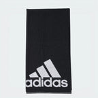 Focuses on the full front profile of the neatly folded towel, highlighting the crisp, high-contrast white adidas Badge of Sport logo block printed squarely against the rich black terry loop background.