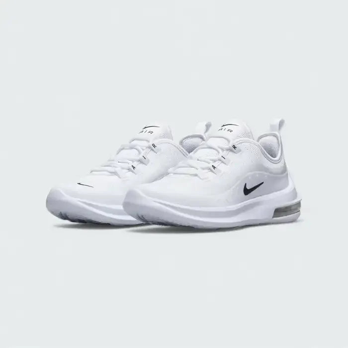 Angled view of two Nike Air Max Axis Children's trainers in white and black, side by side, showcasing their modern aesthetic and lightweight construction.