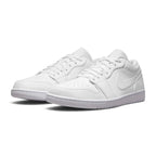 Three-quarter forward angle of the Air Jordan 1 Low trainers, showcasing their classic 1985 basketball aesthetic and clean monochromatic color-blocking.