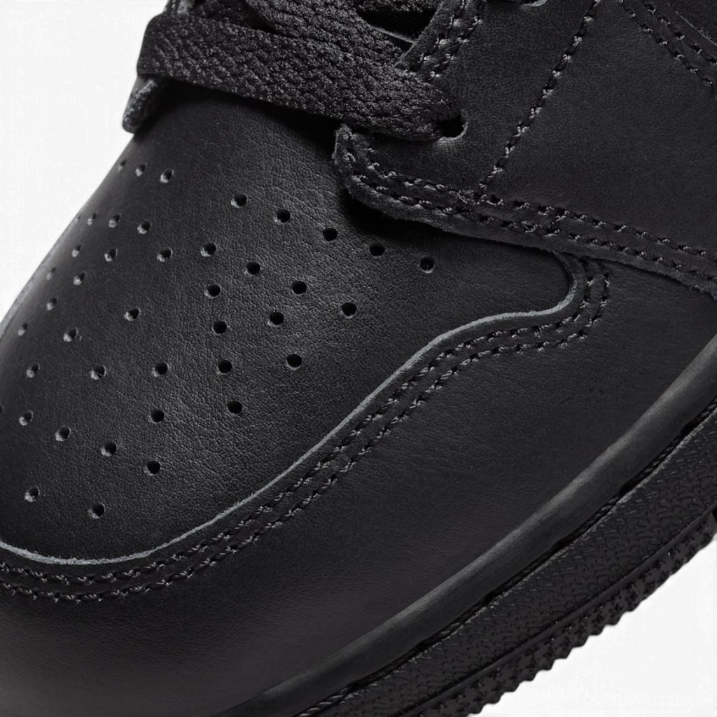 Macro focus on the forefoot and eyestay, detailing the perforated toe box leather texture, tonal stitching, and flat black laces.