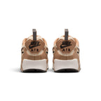 Focuses on the rear profile, highlighting the raised rubber heel tab with debossed Nike Air branding, protective mudguard wrap, and the wide footprint of the foam midsole base.