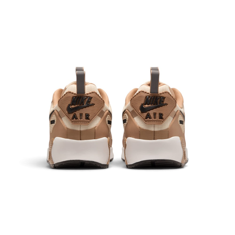 Focuses on the rear profile, highlighting the raised rubber heel tab with debossed Nike Air branding, protective mudguard wrap, and the wide footprint of the foam midsole base.