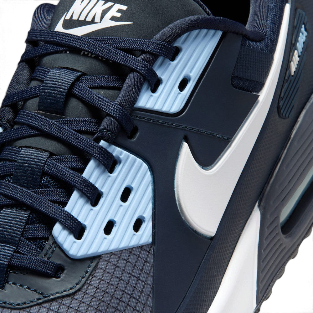 Close-up of a Nike sneaker in navy blue, black, and light blue, showing the side profile with the white Swoosh logo and textured panels.