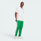 Emphasising the sharp visual contrast of the premium embroidered white Trefoil logo standing proud against the rich green fabric backdrop.